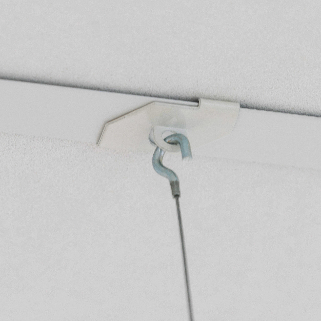Close-up of a hanging electrical cord looped through a white ceiling mount, suspended from a light-colored ceiling surface.
