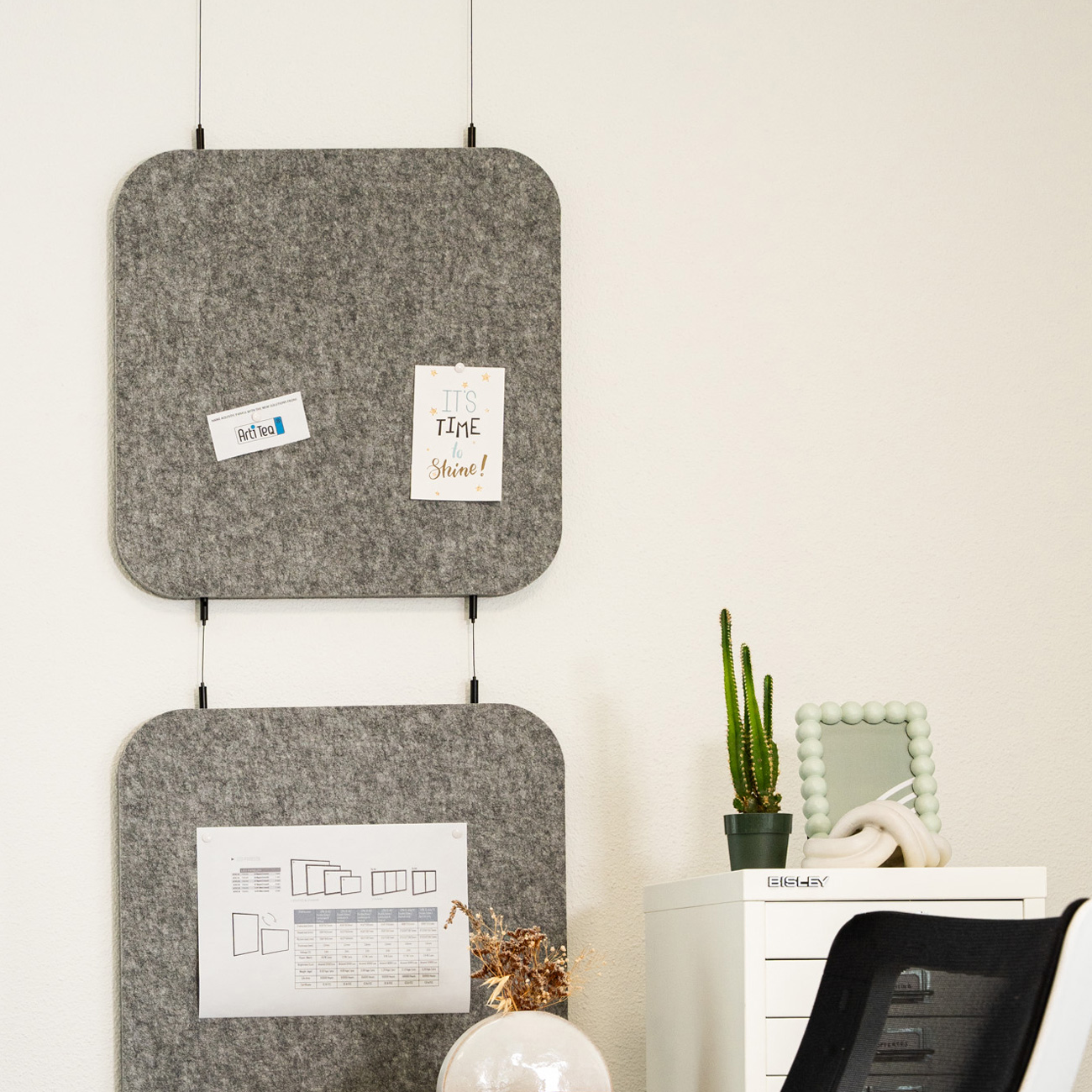 Workspace with two grey felt panels, notes pinned, a cactus on a white cabinet, and a beaded-frame mirror.