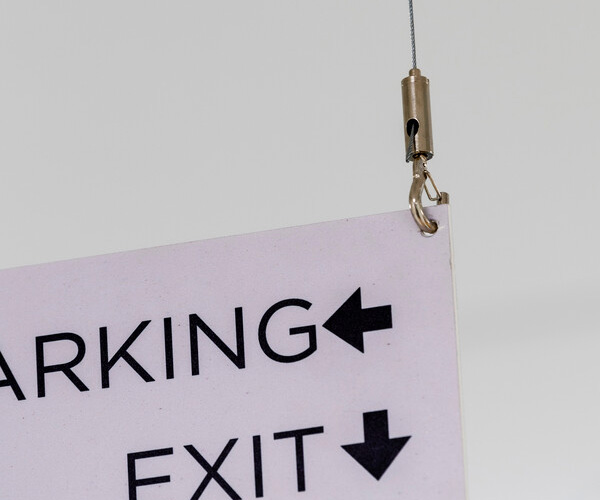 Partial pink sign showing 'PARKING' with a left arrow and 'EXIT' with a downward arrow, hanging by a cable.